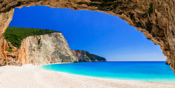 Turquoise sea and a white beach framed by a rocky cave